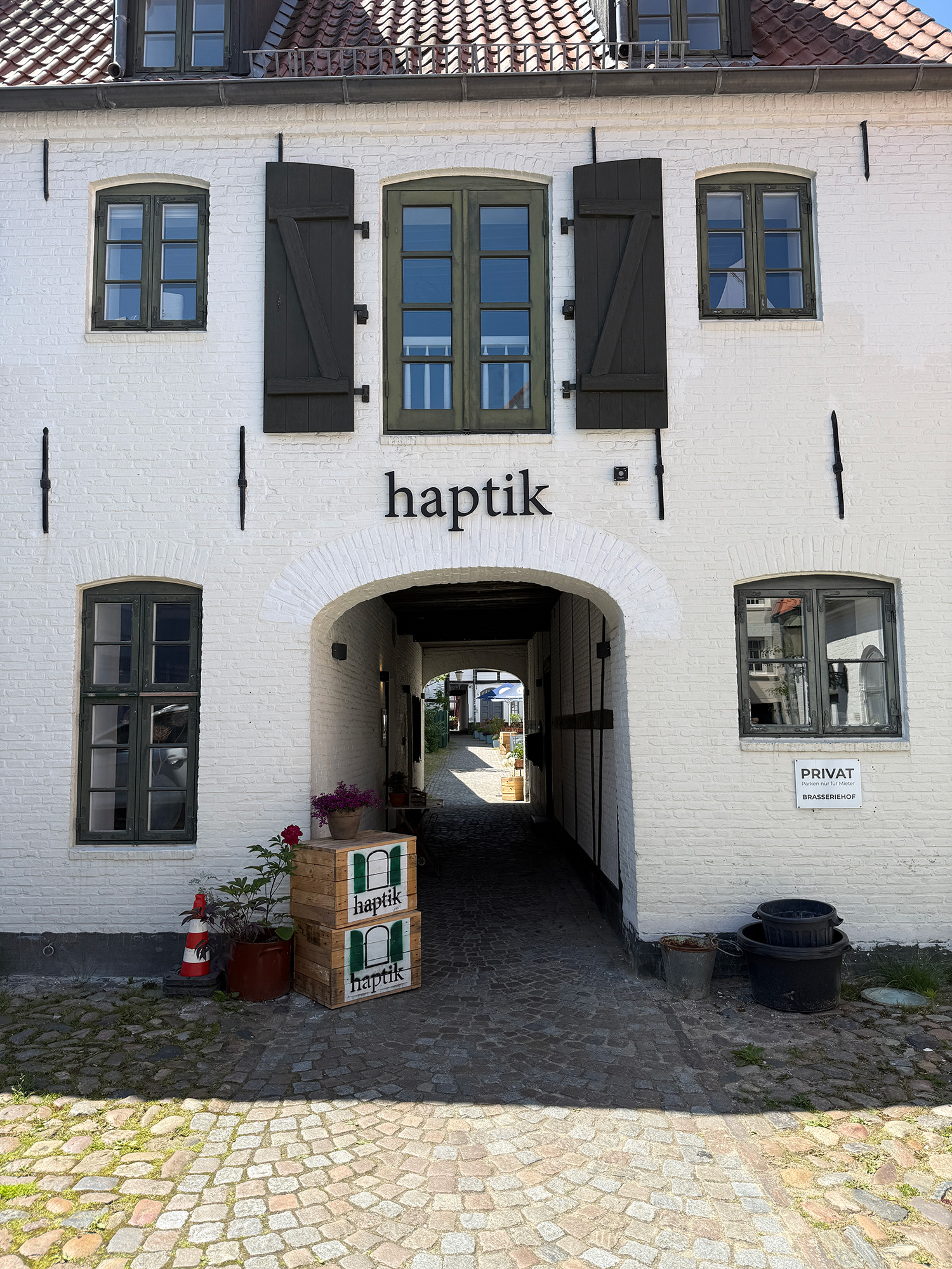 Altbau Sprossenfenster Schriftzug Pflastersteine Torbogen